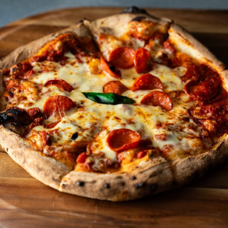 Pepperoni Pizza Pepperoni pizza with melted cheese on a wooden board.