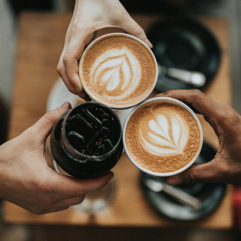 Clinking Coffee Cups Three cups of coffee clink together, two hot lattes and one iced coffee.